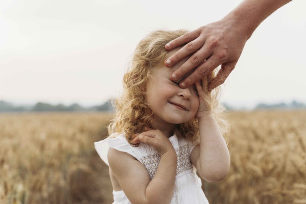 dad touching toddlers head at sunset